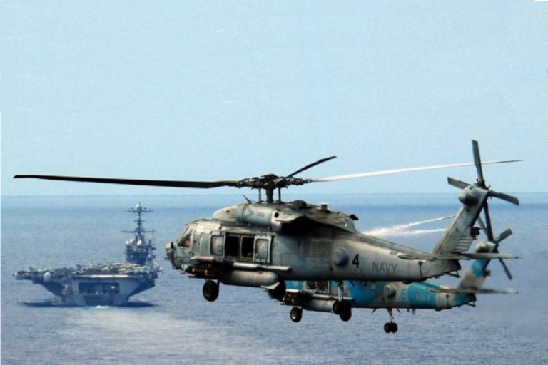 2 helos approaching an aircraft carrier